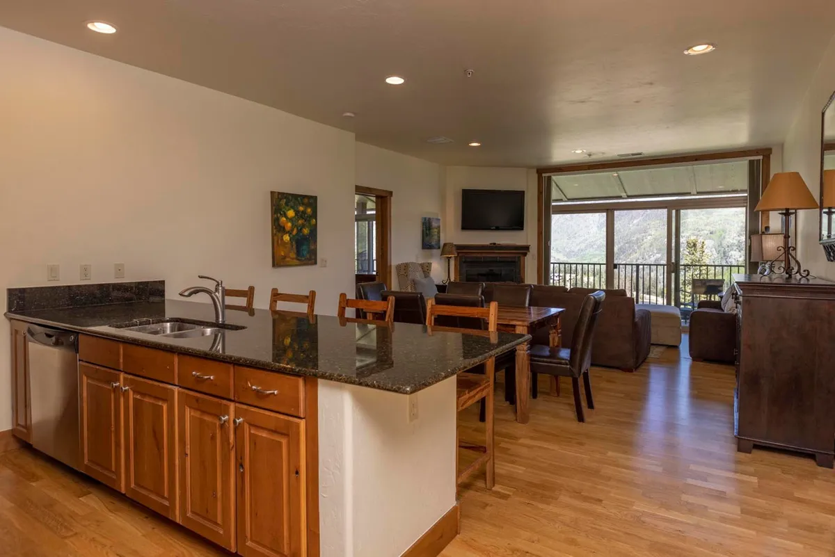 An open-concept kitchen and dining area with a central kitchen island, large windows offering ample natural light and views, and a dining space designed for relaxation and togetherness.